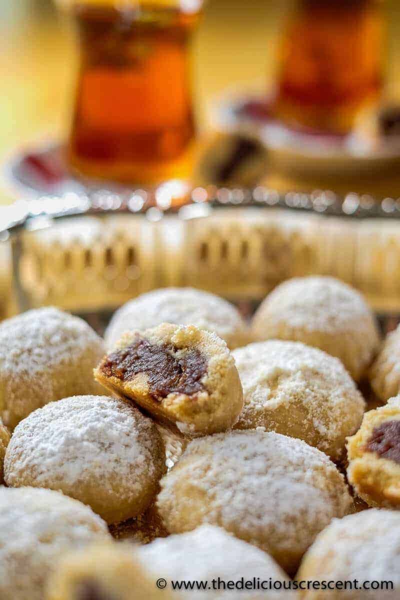 Maamoul cookies served on a plate with some cookies cut into half.