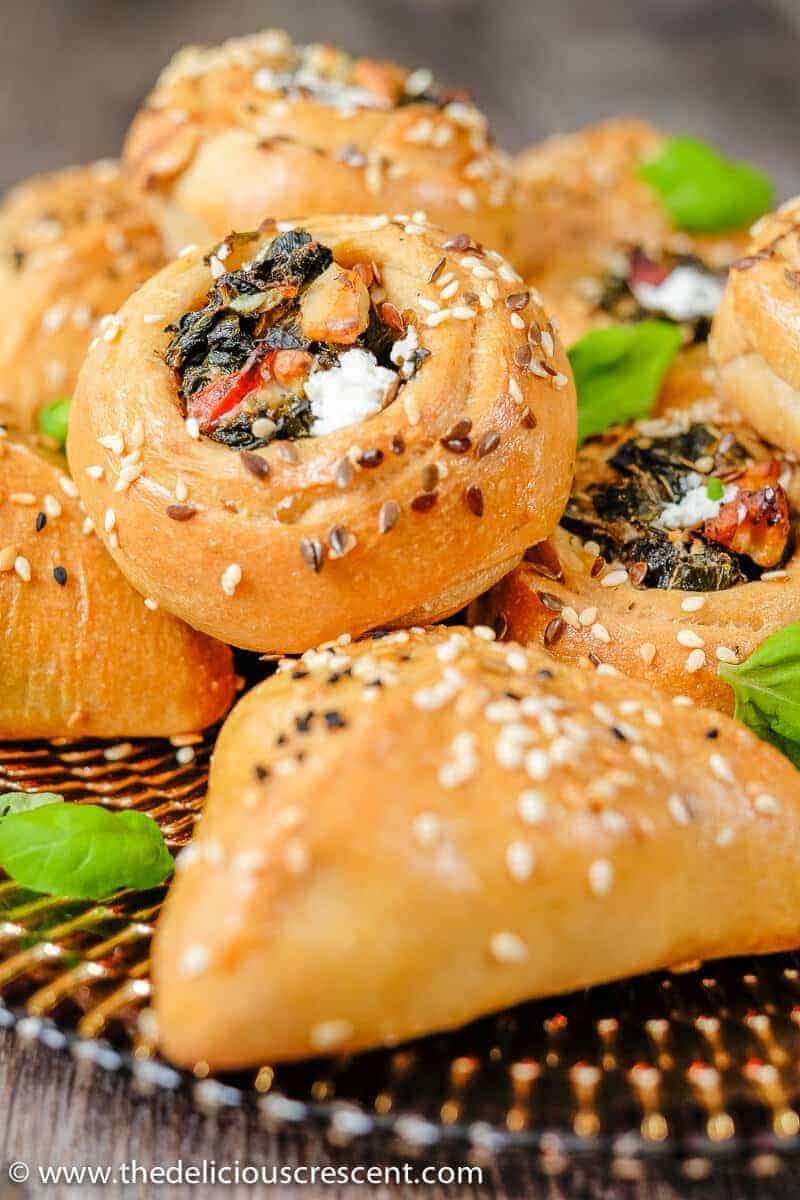 A round middle eastern pie filled with greens and feta cheese placed on other pies.