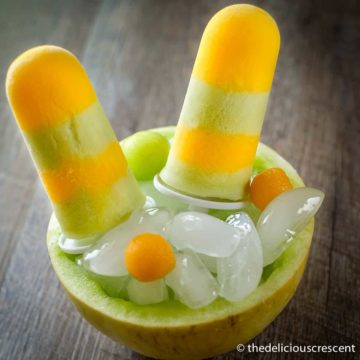 Melon popsicles placed over ice inside a melon.