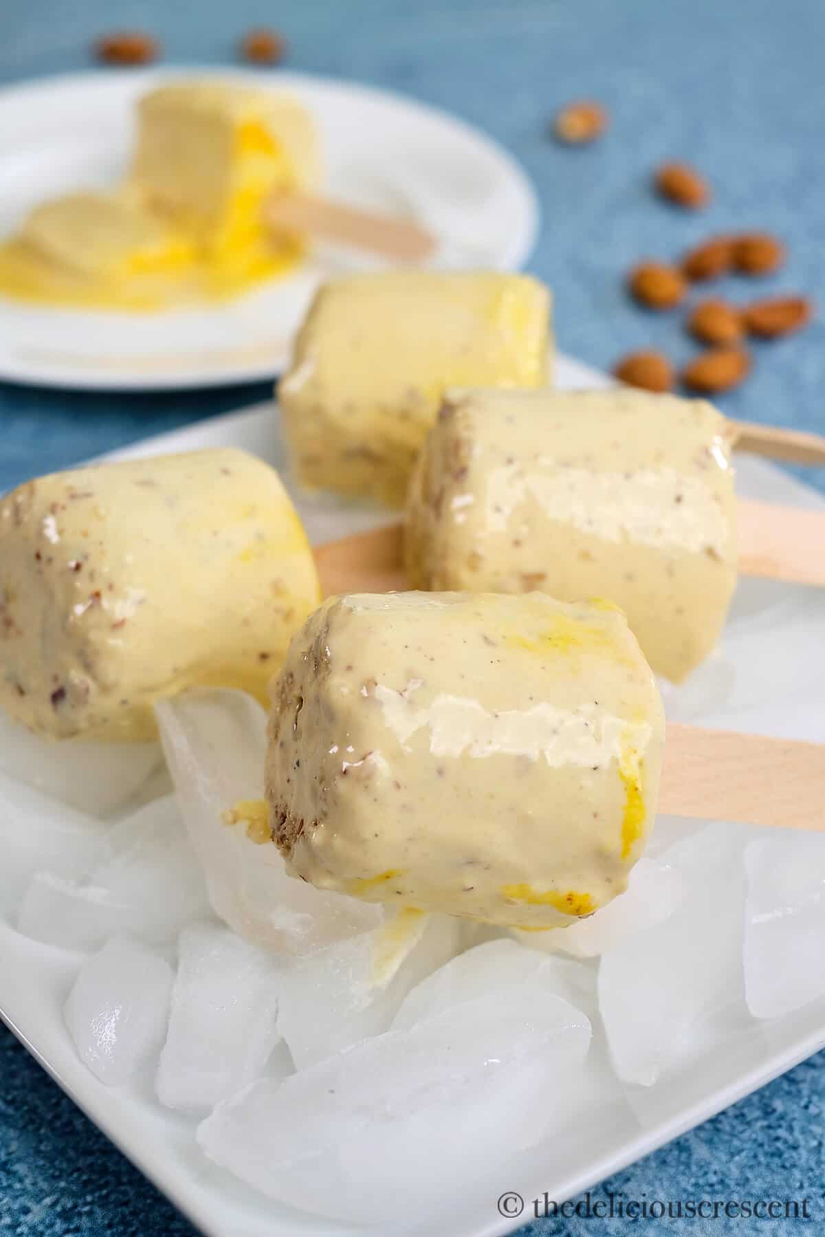 Four delicious malai kulfis on a plate full of ice.