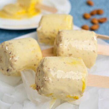 Close view of four delicious malai kulfis on a plate full of ice.