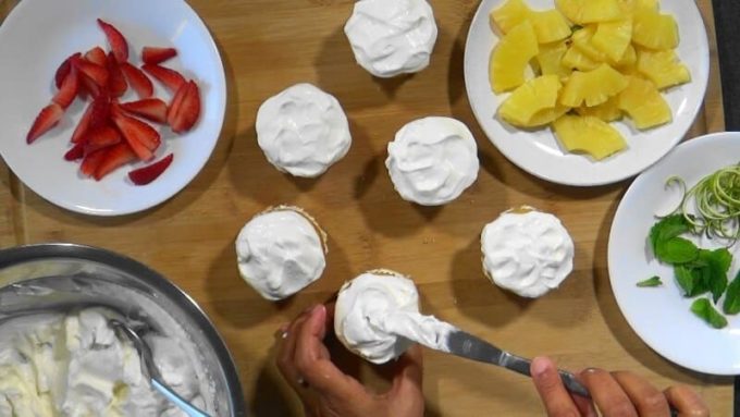 Icing the top ofpineapple cupcakes with yogurt cream