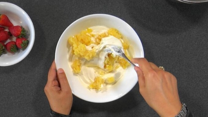 Mixing crushed canned pineapple with yogurt cream to make the filling