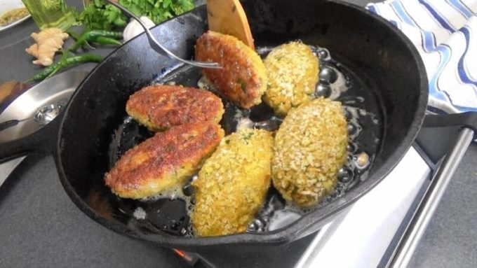 Shallow frying the Indian fish cakes in a skillet.