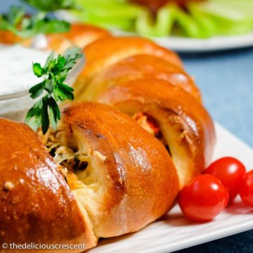 Mediterranean tuna melt crescent ring with a lemon dill sauce served on a plate.