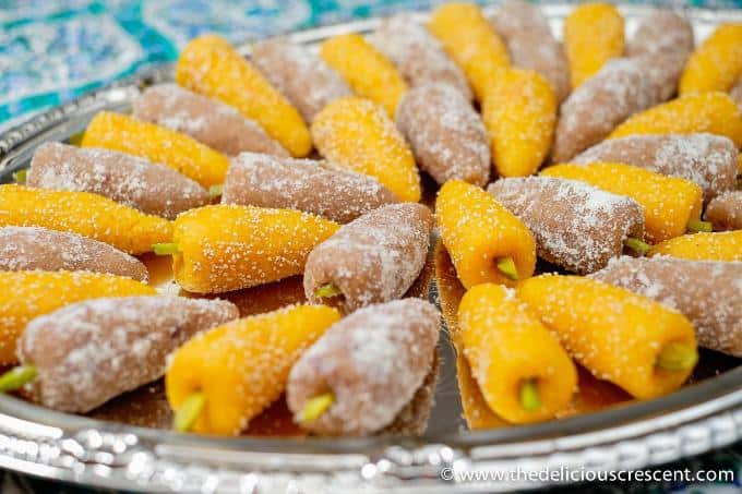 Tan and orange color homemade Persian mulberry marzipan candies arranged alternatively on a plate.