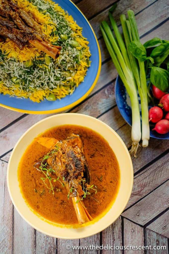 Overhead view of Persian dill rice (Baghali Polo) served with lamb shank in gravy.