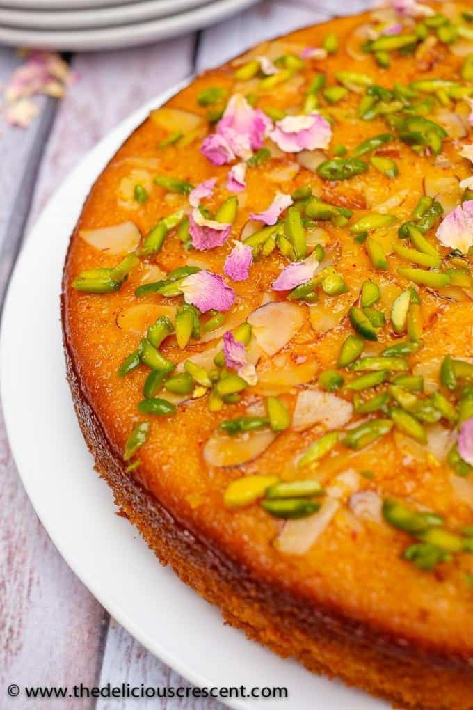 Persian love cake is moist, spongy and will enchant you with its exotic flavors of rose, cardamom, saffron. Luxuriously packed with almonds and sprinkled with pistachios, it is so easy to make! Great recipe for a traditional dessert to serve for holidays, wedding party or Valentines day. This Persian almond cake with cardamom and pistachios soaked in honey works well with rose water whipped cream. Gluten free and nut free options. #cake #dessert #Persianfood View of Persian love cake from the top.