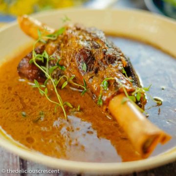 Braised lamb shanks served with a fantastic sauce in a serving dish.
