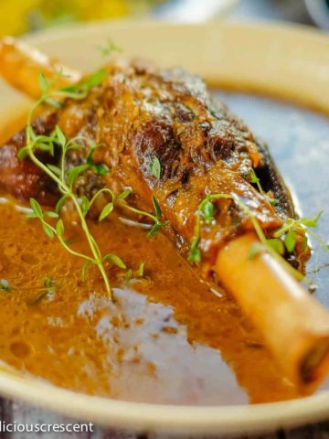Braised lamb shanks served with a fantastic sauce in a serving dish.