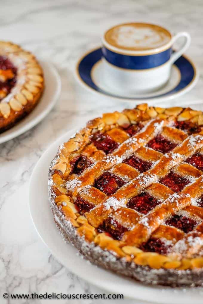 Linzer torte placed on a white plate with a cup of coffee on the side.