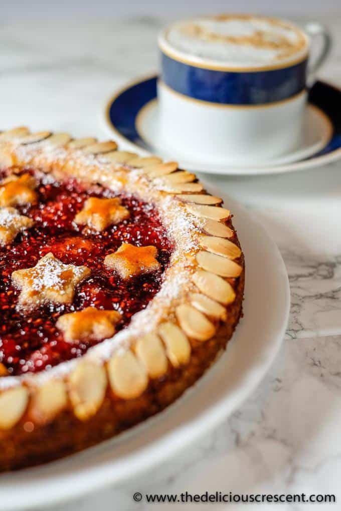 Front view of a decorated Linzer torte with raspberry jam filling.