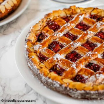 Linzer torte with raspberry filling served with a cup of coffee.