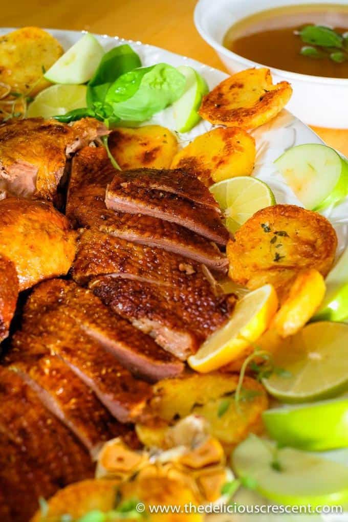 A spiced Roast Goose that is super crispy and golden on the outside, tender and incredibly flavorful on the inside. With this detailed recipe you will learn how to cook it perfectly the very first time! Check the tips for succulent breast meat, tender thigh meat, roasted with spices, apple stuffing. Goose fat makes the best roasted potatoes ever for a great side at dinner! Roasted goose is also low carb, gluten free, nut free, dairy free. #roastrecipes #holidayrecipes #lowcarb Close up view of carved goose on a serving platter
