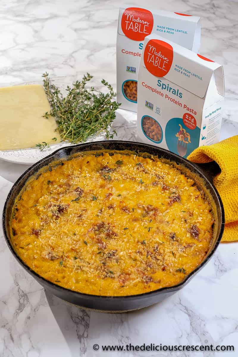 Baked healthy mac and cheese prepared with lentil pasta and served in cast iron skillet.