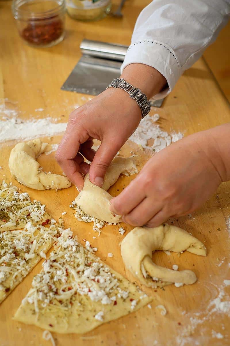 Shaping crescent rolls filled with cheese, spices and herbs.