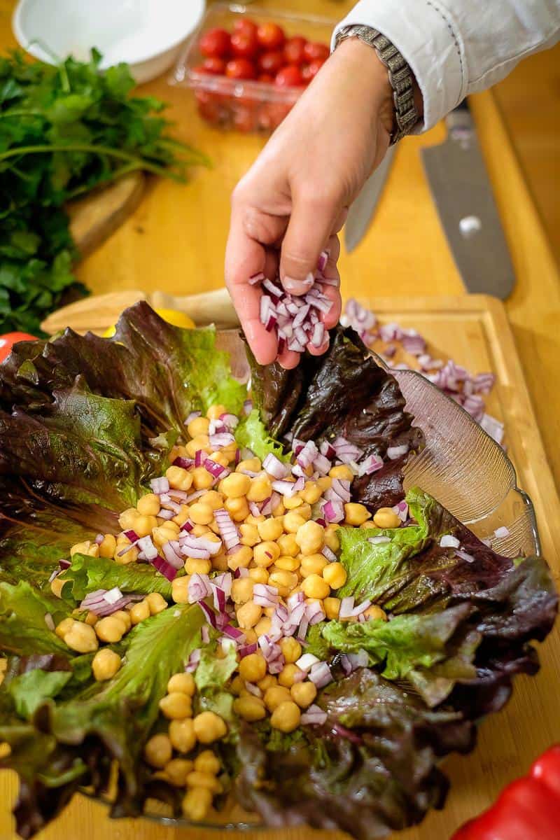 Adding chopped onions to a salad.