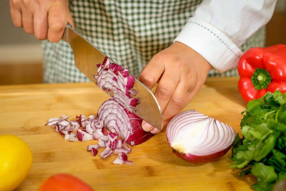 Blog author chopping red onions on the table.