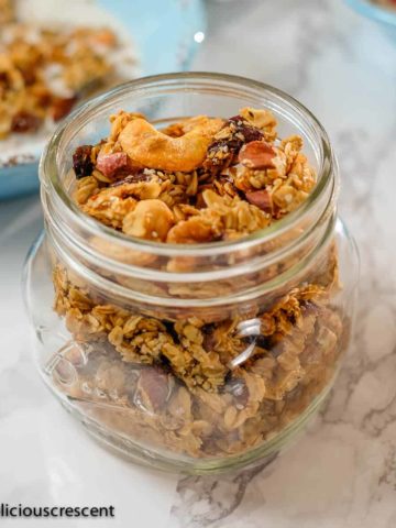 Homemade granola with cashews and cardamom stored in a glass bottle.