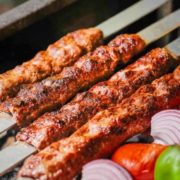 Persian kabob koobideh arranged over flat breads along with grilled vegetables.