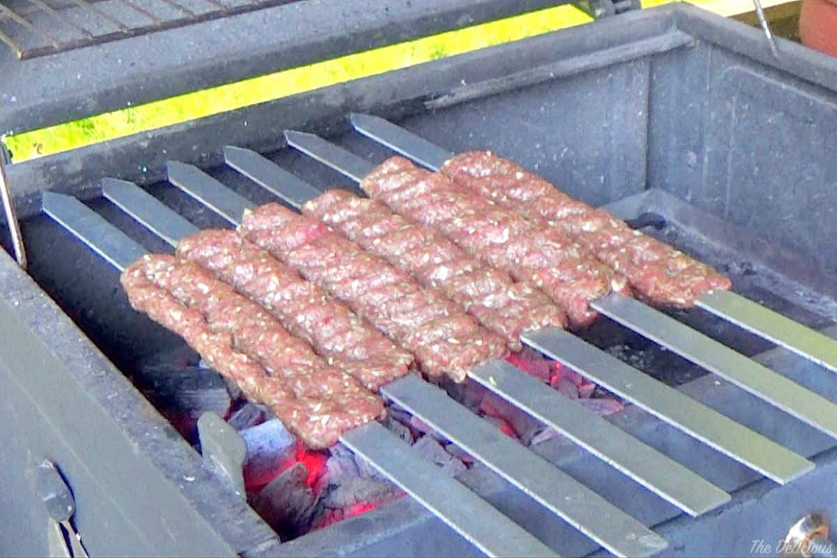 Persian ground meat kebabs placed on a charcoal grill.