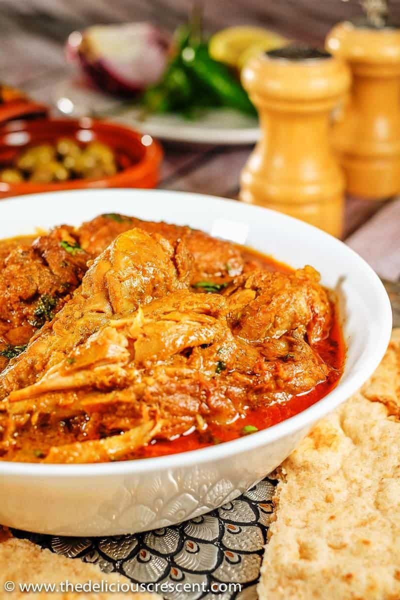 Authentic Indian chicken korma served in a white dish and placed on a table with naan on the side.