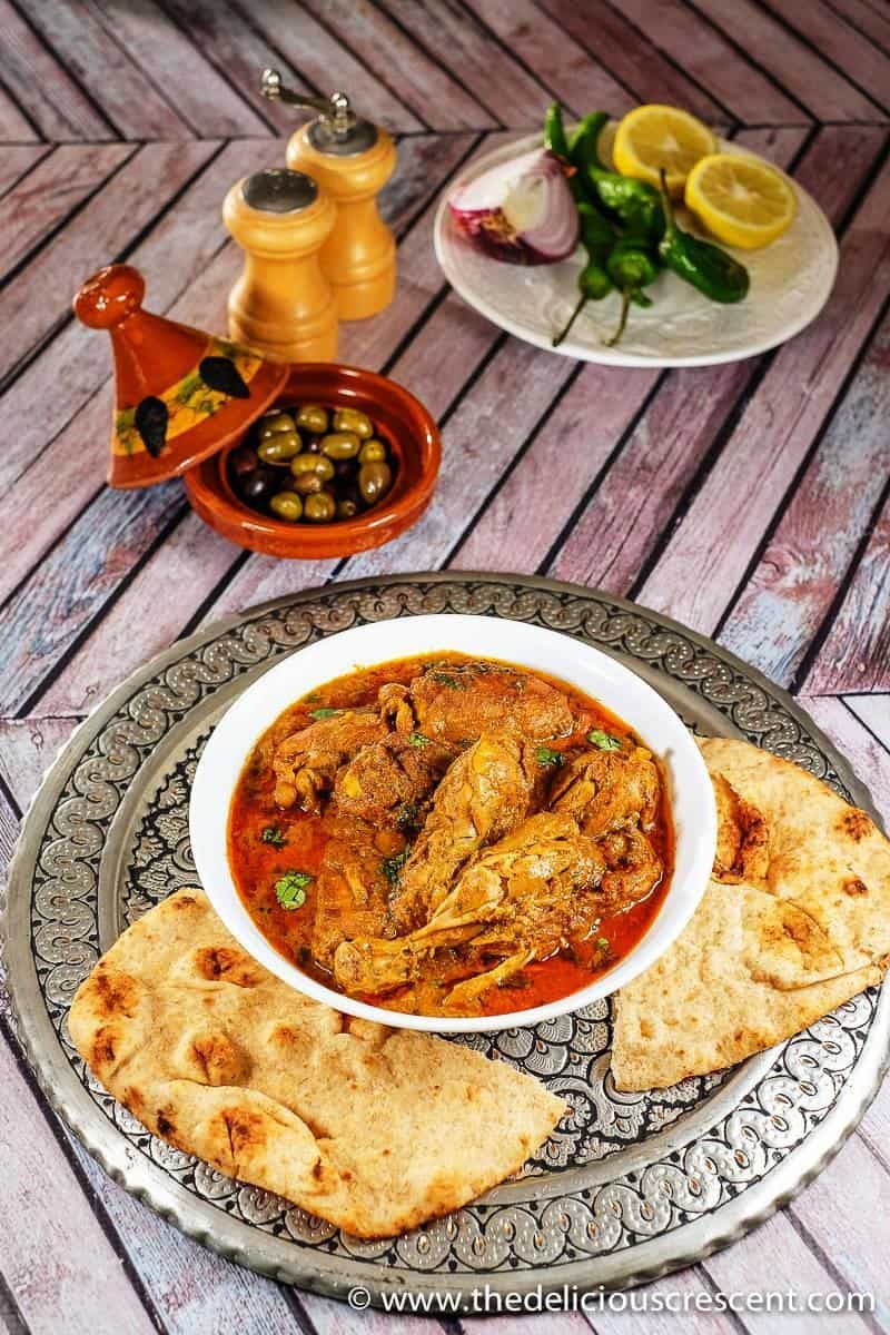 Overhead view of chicken cooked in a fragrant spiced yogurt sauce and served with naan.