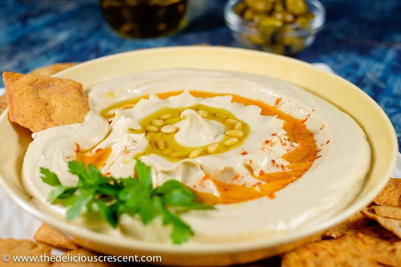 Homemade hummus served in a cream bowl along with pita chips.