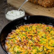 Baked zucchini firttata in a cast iron skillet served with a dip.