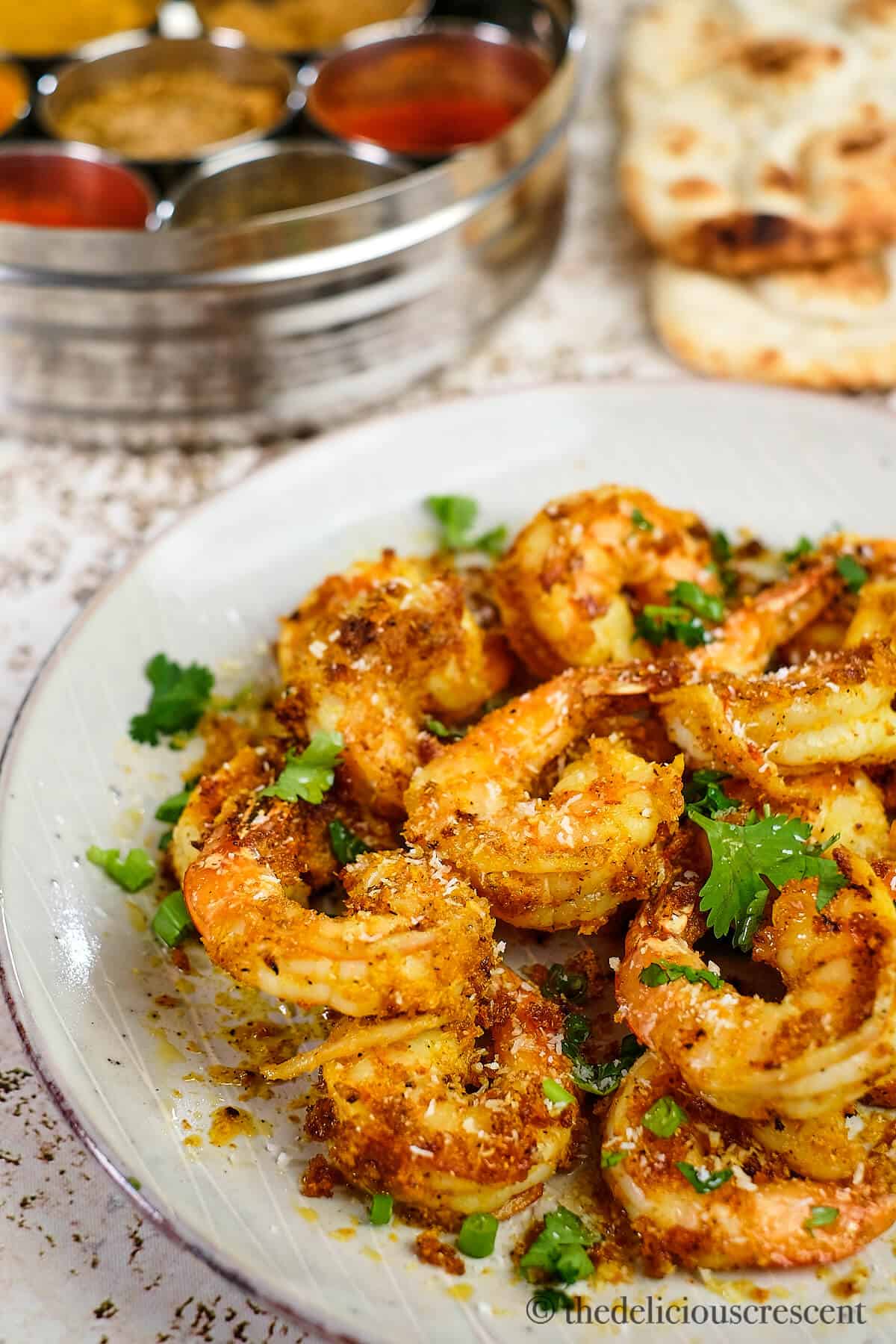 Side view of sauteed shrimp in a white plate.