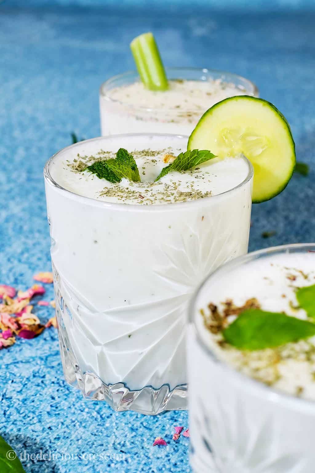 Yogurt drink in a glass with a cucumber slice on the rim.