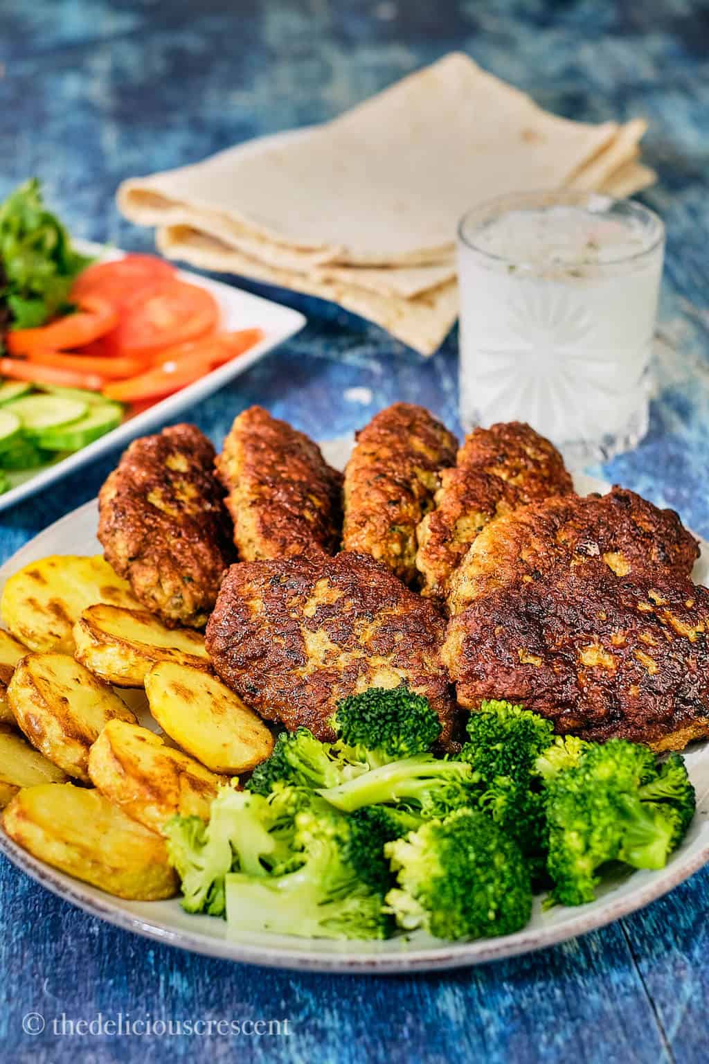 Persian kotlet served with a side of potatoes and broccoli.