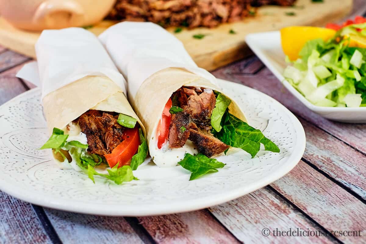 Two shawarma wraps on a white plate.