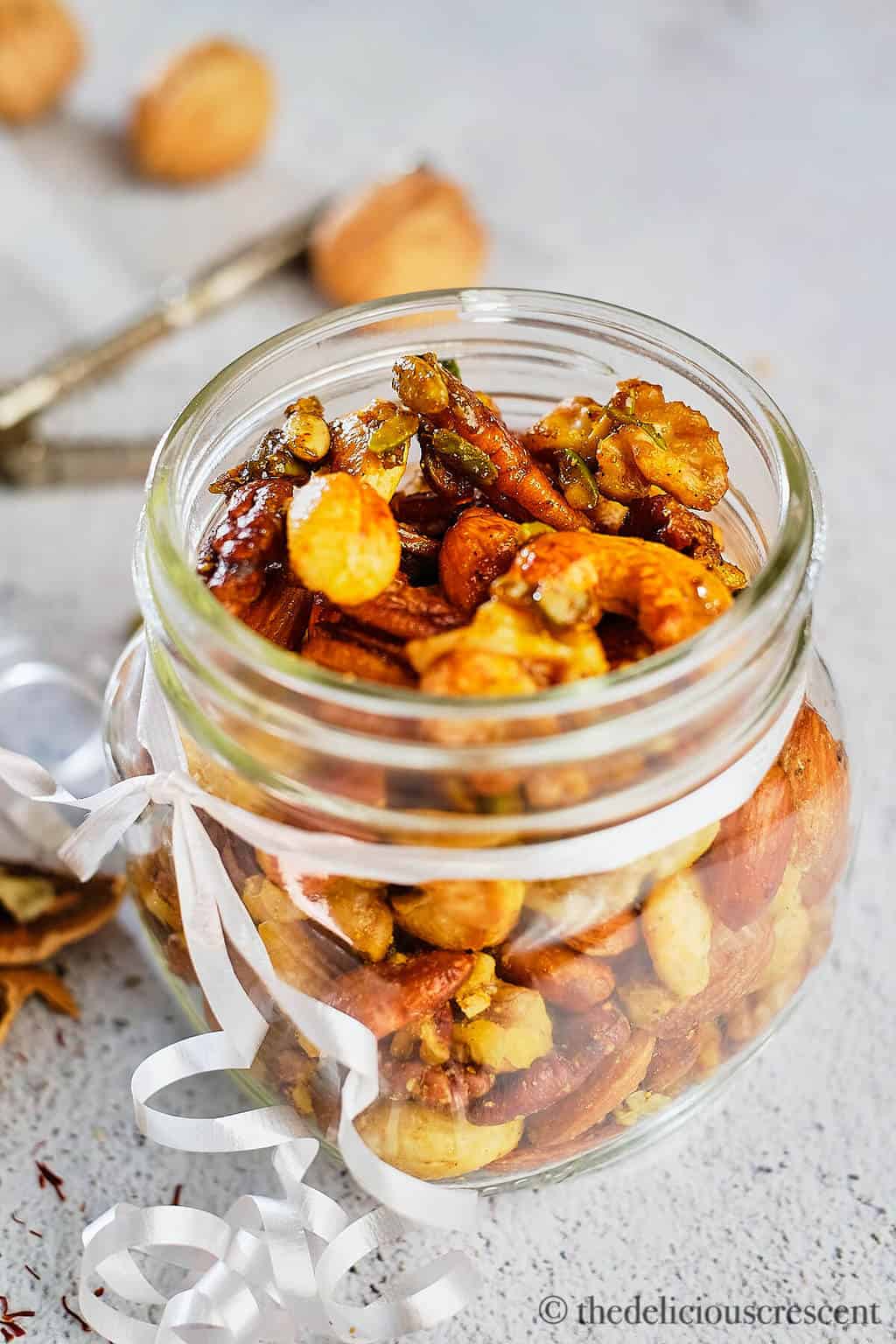 A glass container with almonds, cashews, pecans and walnuts spiced with cardamon, saffron and maple syrup.