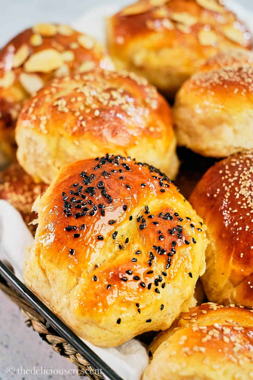 Soft honey wheat rolls topped with a variety of seeds and arranged in a basket.