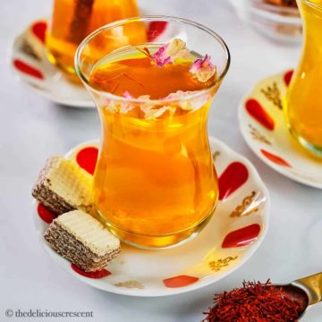 Saffron tea served in a glass cup and placed on a table.