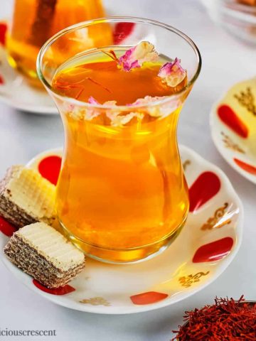 Saffron tea served in a glass cup and placed on a table.