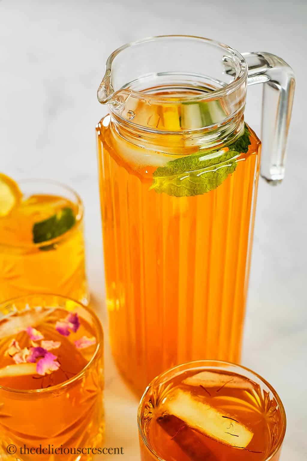 A pitcher full of exotic iced drink prepared with aromatic ingredients.