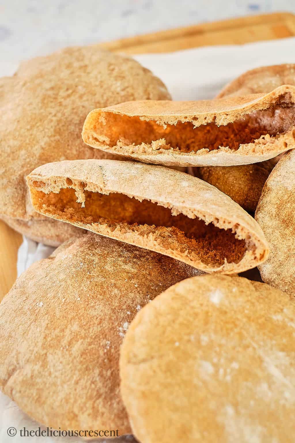 Whole wheat pita bread halves placed among a stack of breads.