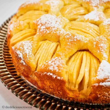 German apple cake dusted with sugar and served on a plate.