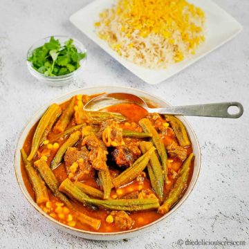 Okra stew with lamb served in a grey bowl with brown rice.