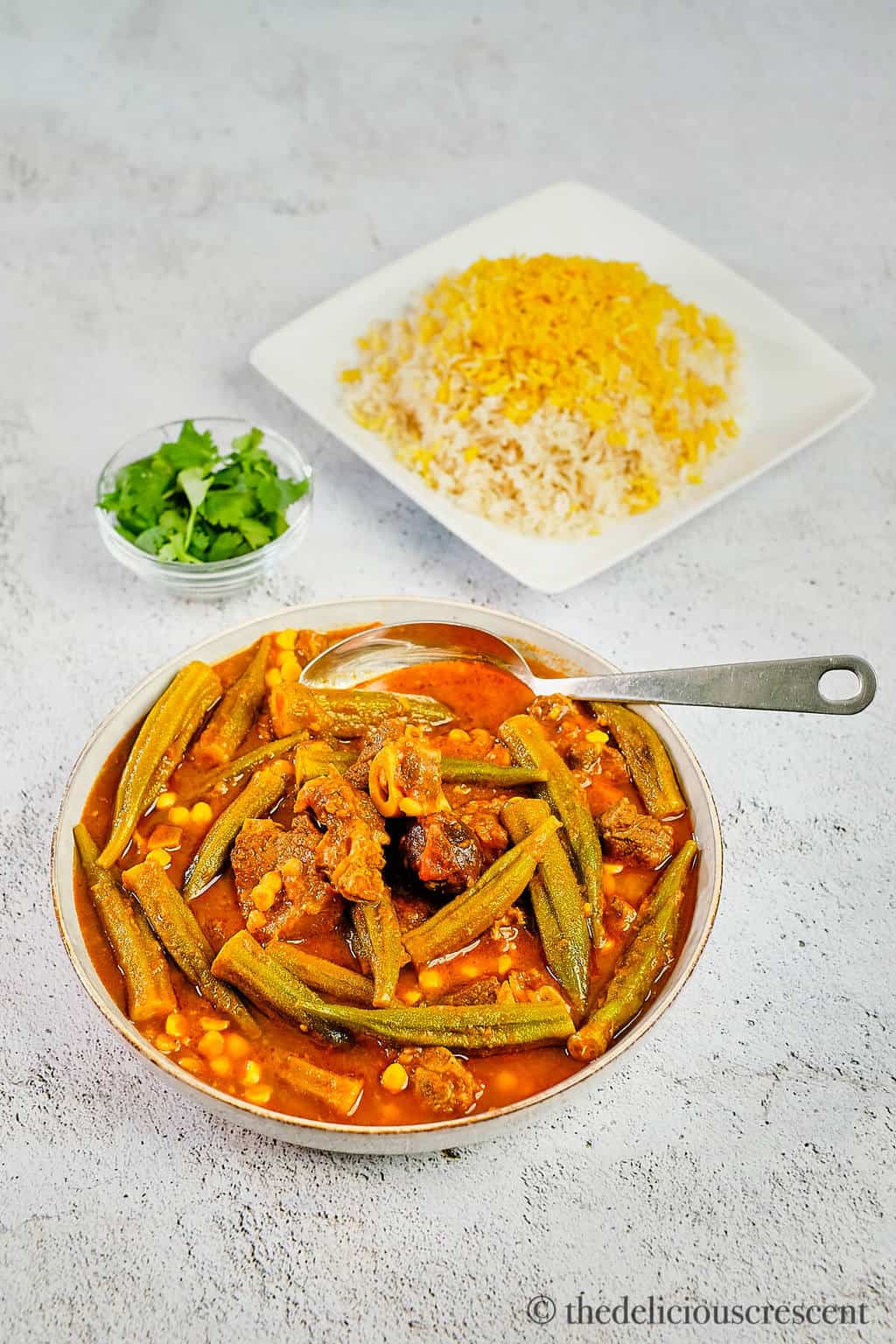 Okra stew with lamb served in a grey bowl with brown rice.