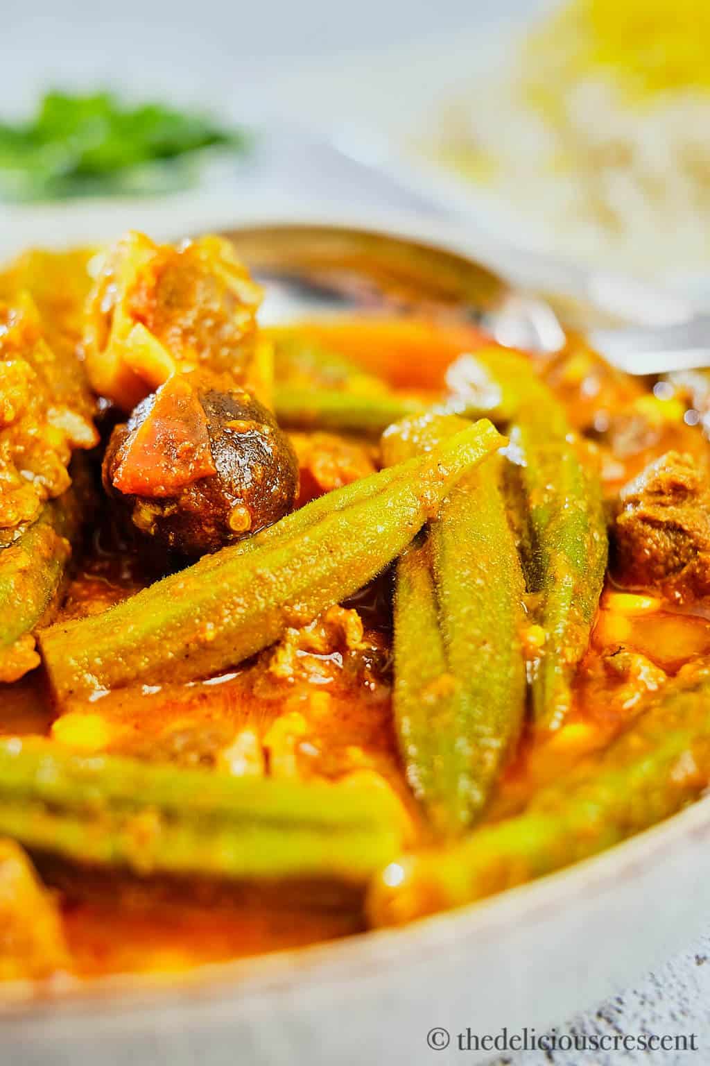 Khoresh Bamieh prepared with lamb and served in a grey bowl.