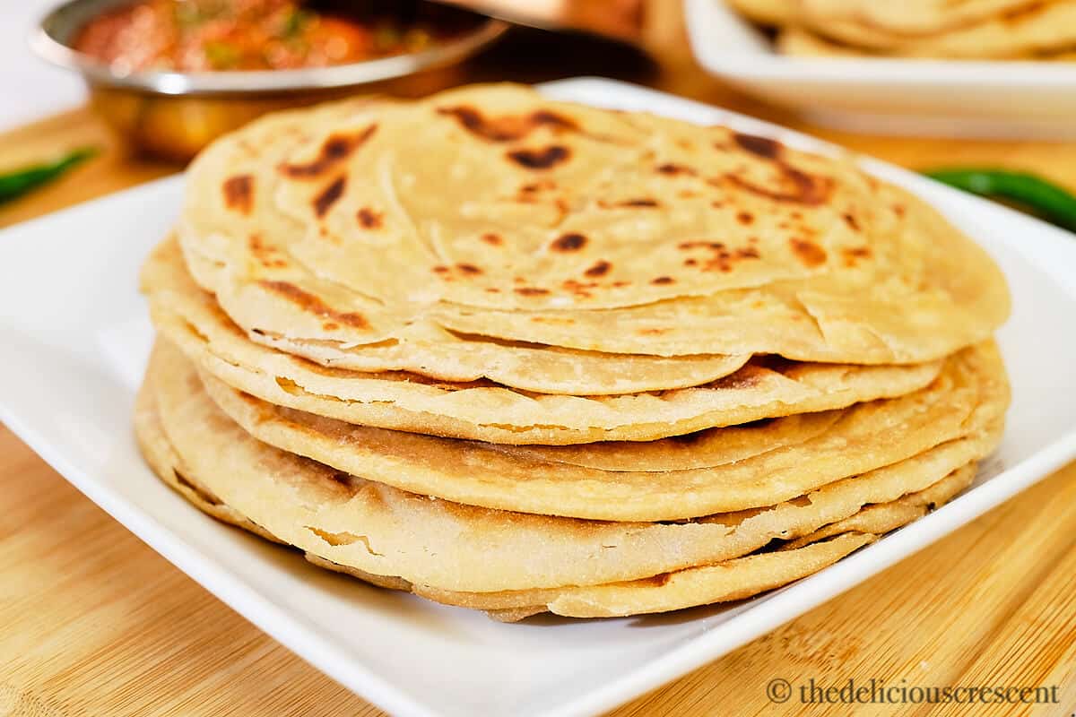 Indian layered flatbread (parathas) stacked on a plate.