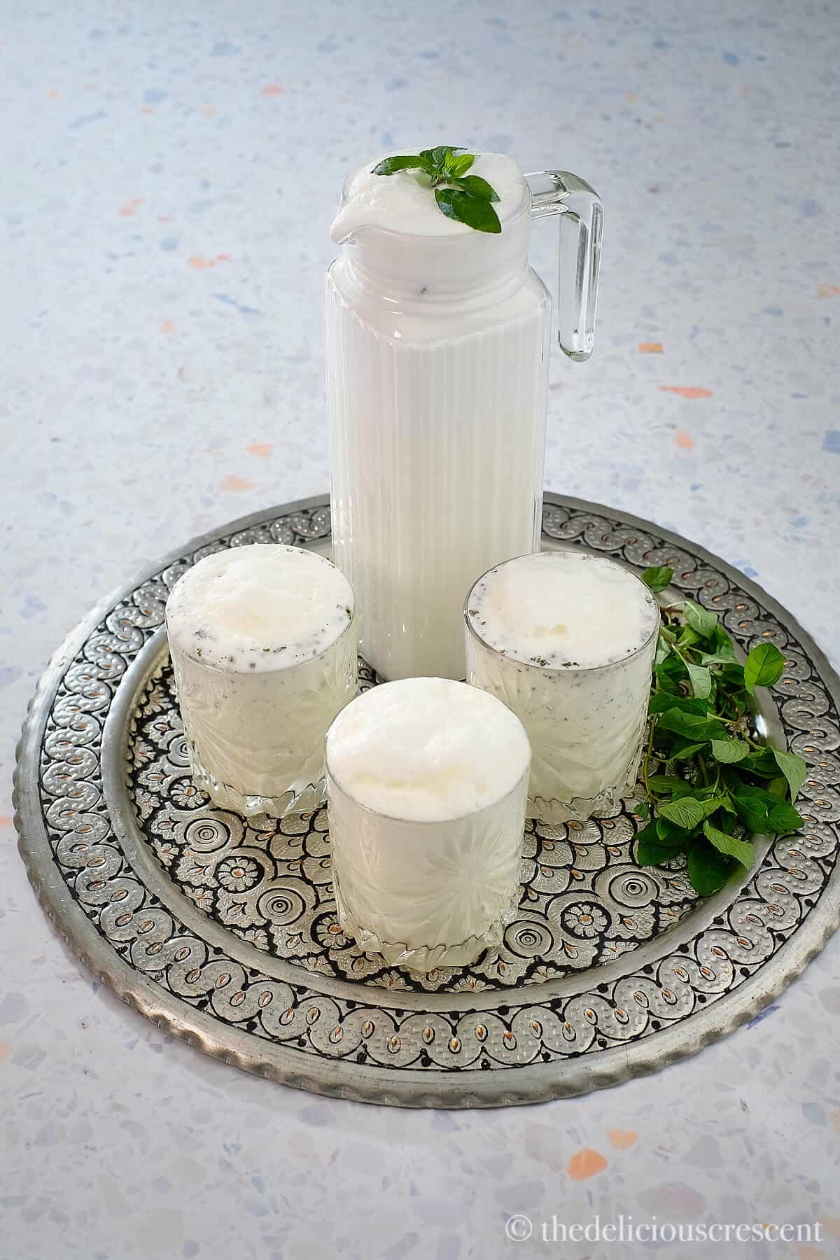 A pitcher with savory yogurt drink along with two glasses.