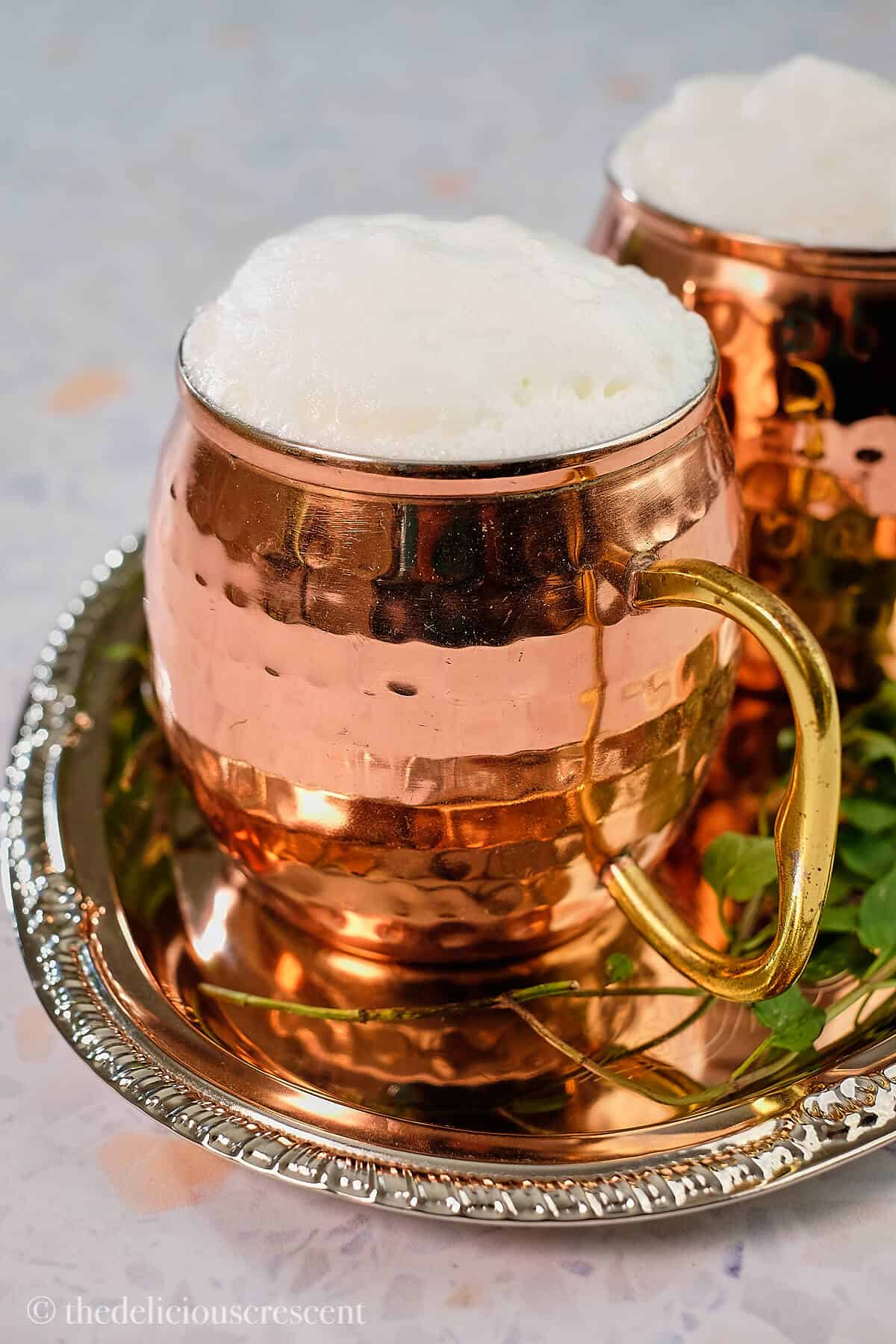 A copper mug full of Ayran with foam on top.