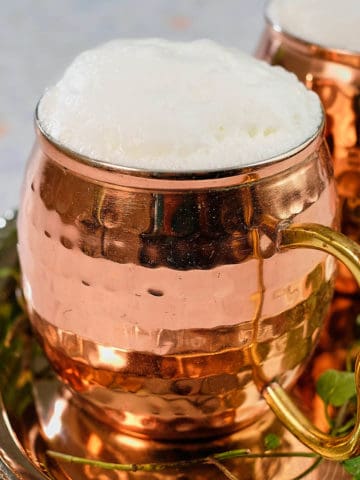A copper mug full of Ayran with foam on top.