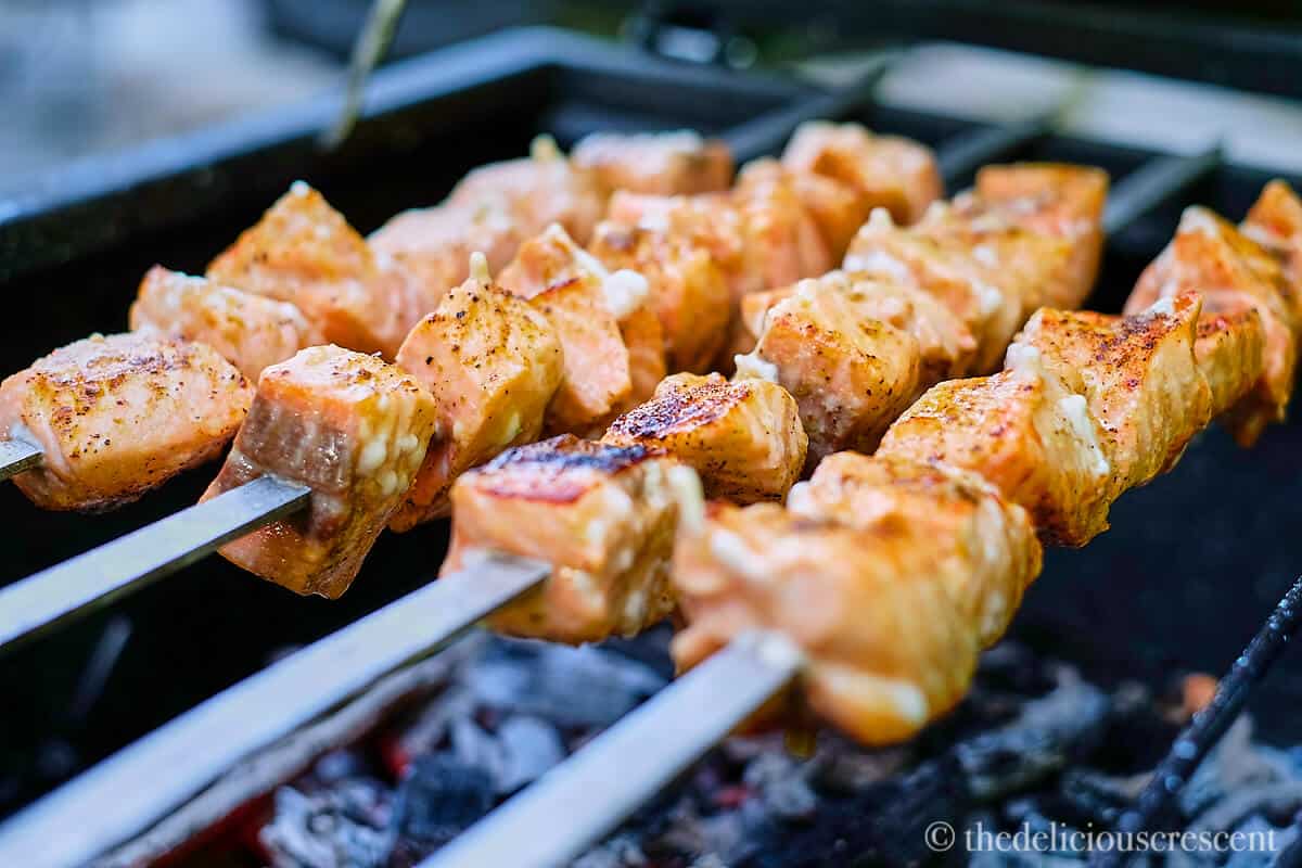 Salmon skewers placed on a charcoal grill.