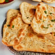 Naan breads arranged on a metal platter.