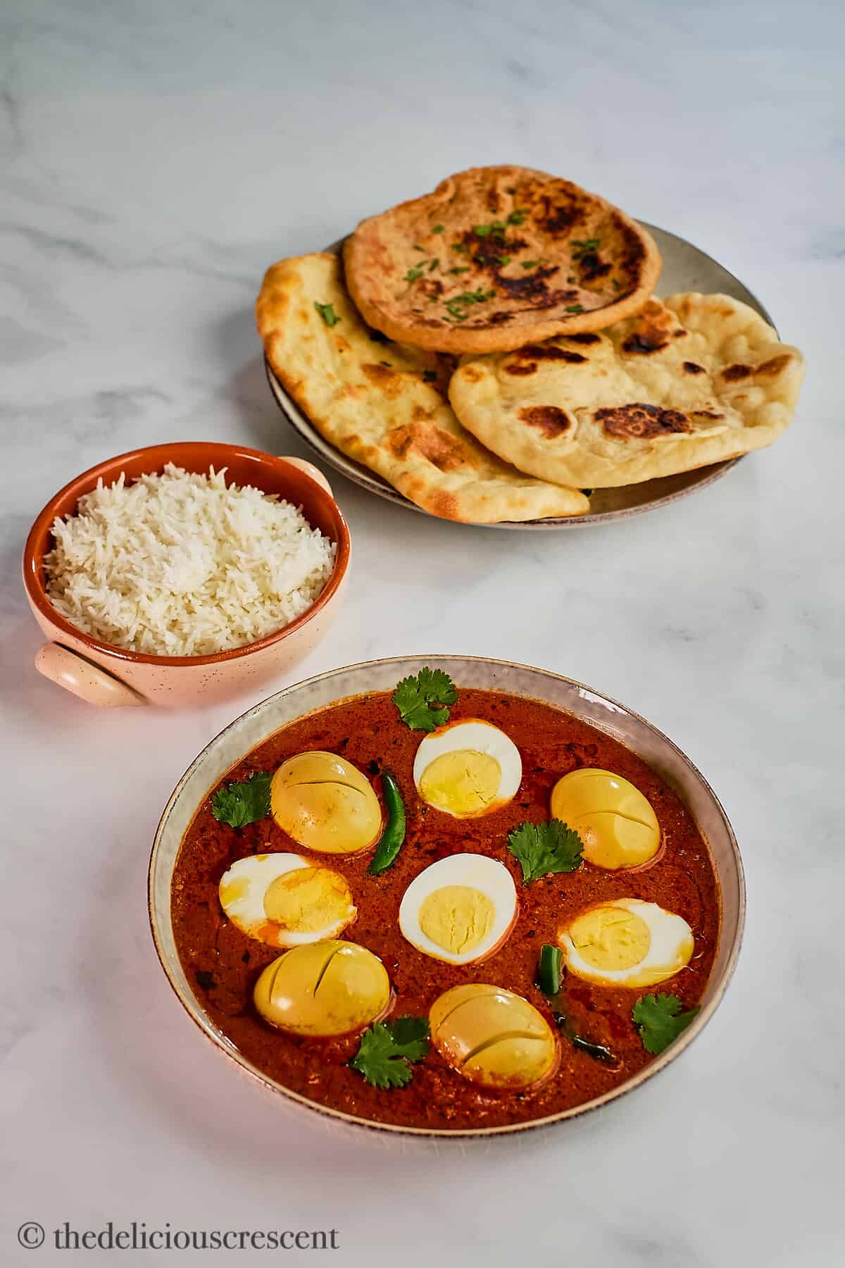 Egg curry served with naan and rice.